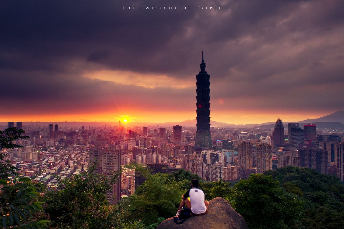 man in white shirt sitting on rock during sunset