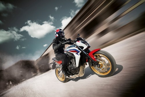 Image man in black and white motorcycle suit riding orange and black sports bike