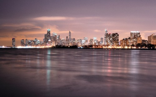 Image city skyline across body of water during night time