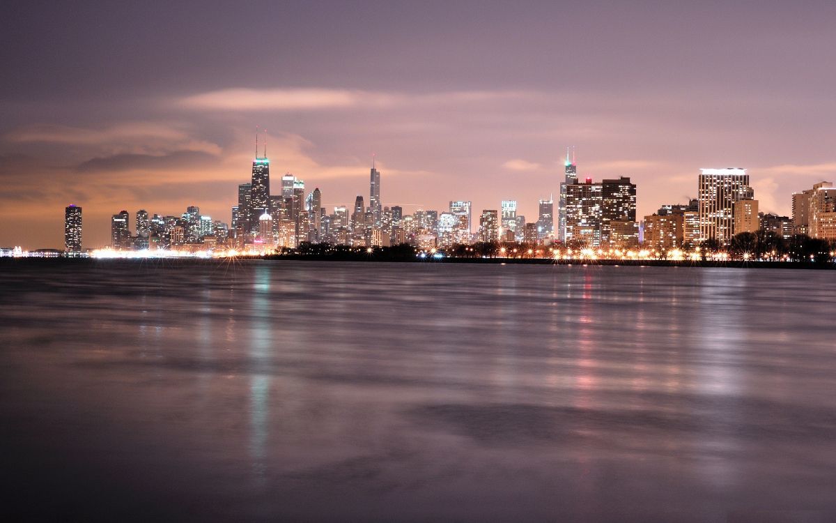 city skyline across body of water during night time