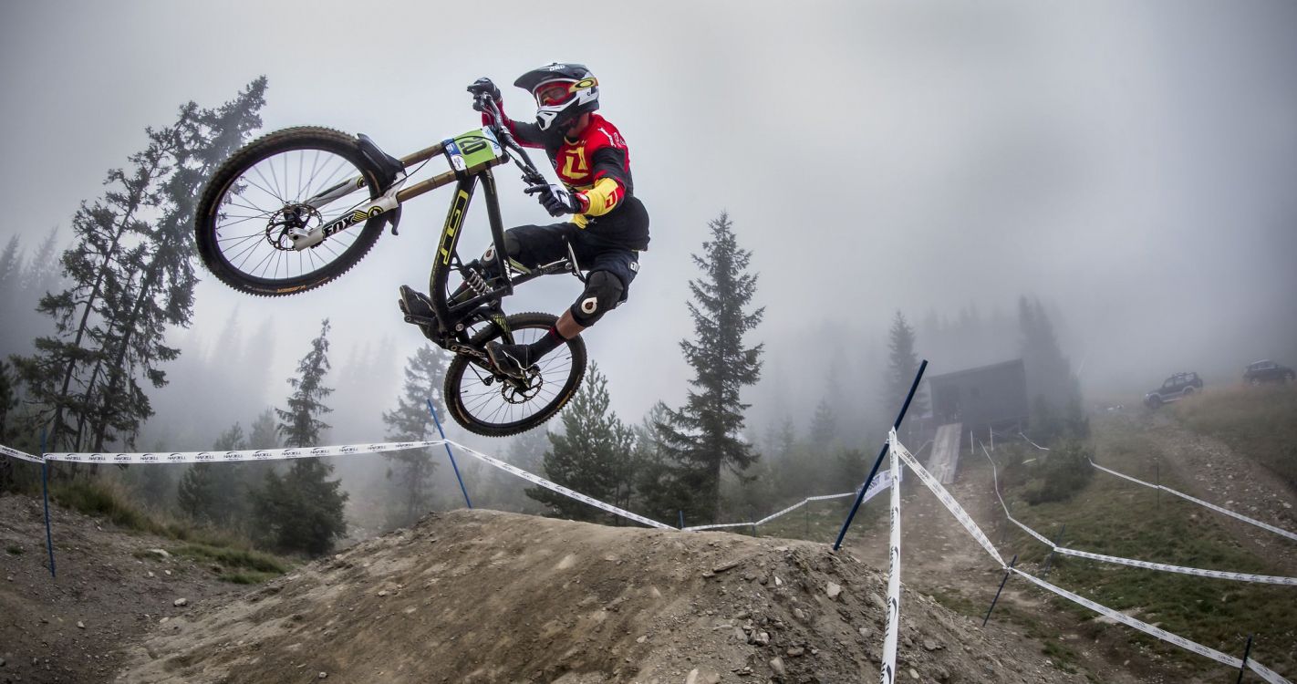 man in black jacket riding on white and black mountain bike