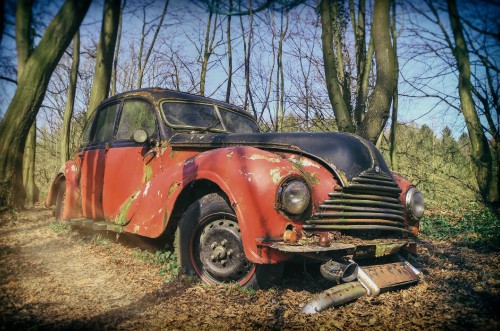 Image red and black vintage car parked on brown grass field during daytime