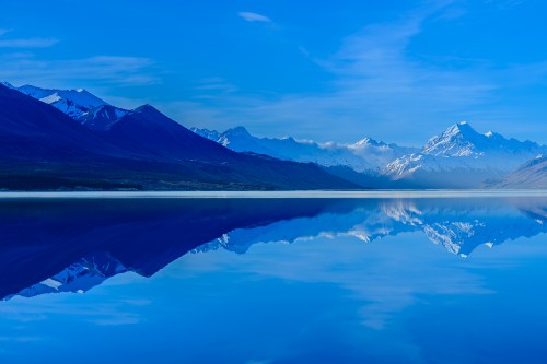 Image body of water near mountain under blue sky during daytime