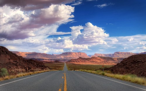 Image gray asphalt road near brown mountains under blue and white sunny cloudy sky during daytime