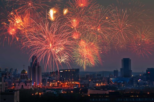 Image fireworks display over city buildings during night time