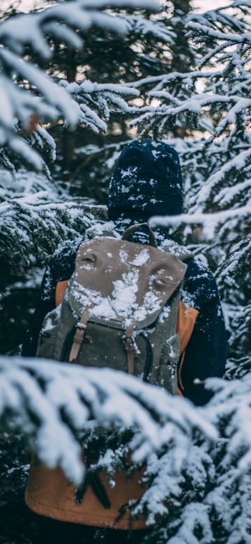 Image man in black jacket and brown pants standing on snow covered ground during daytime