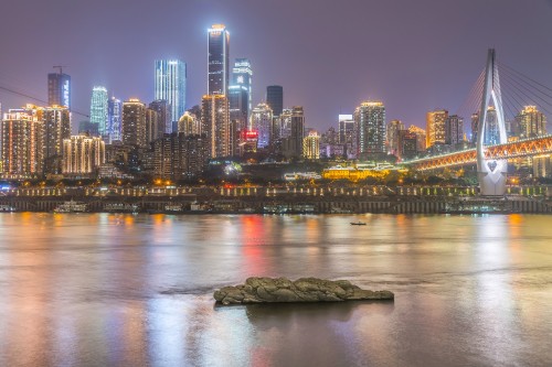 Image city skyline across body of water during night time