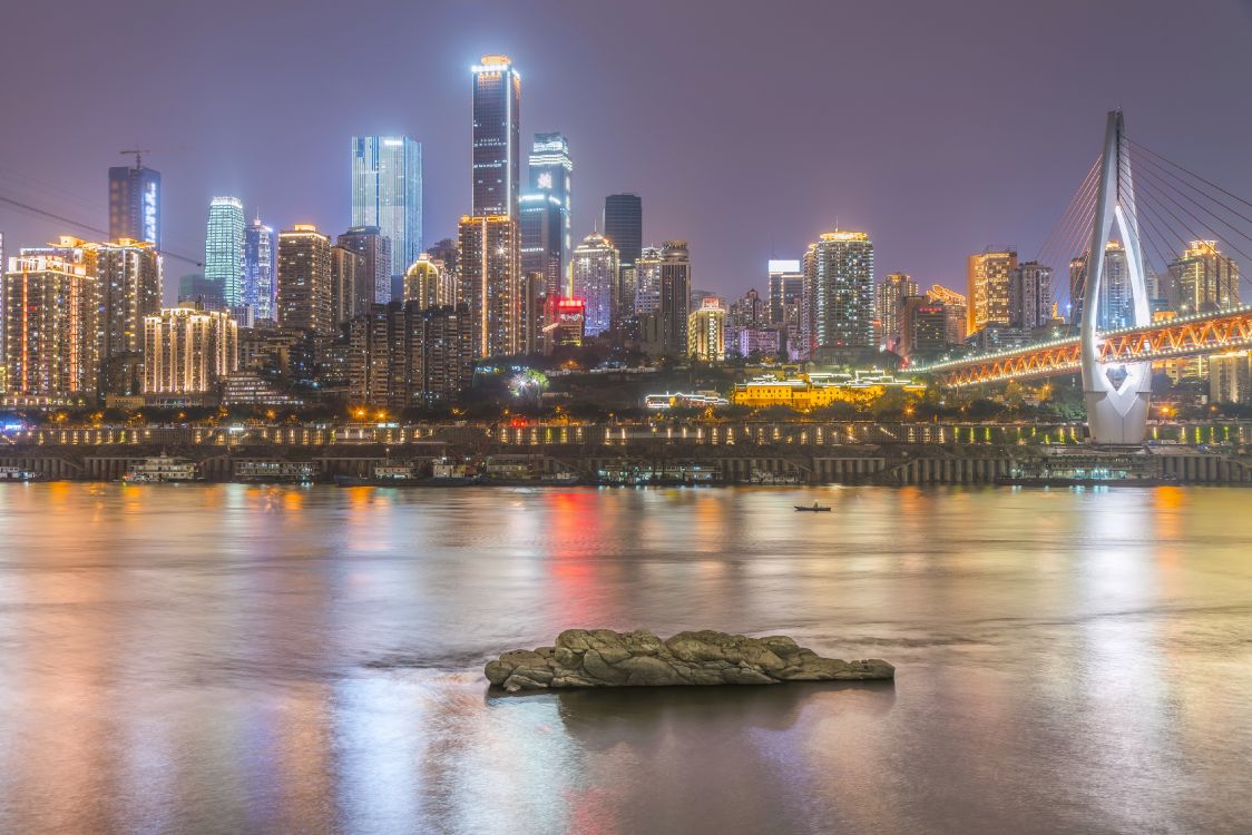 city skyline across body of water during night time