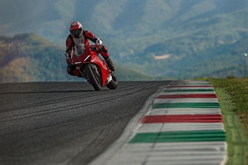 Image man in red and black motorcycle suit riding on motorcycle on road during daytime