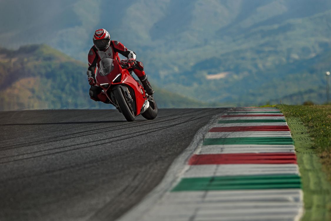 man in red and black motorcycle suit riding on motorcycle on road during daytime