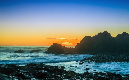 Image ocean waves crashing on rocks during sunset