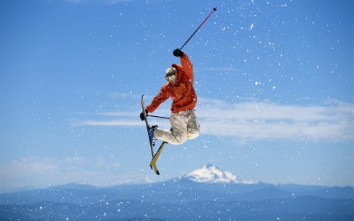 Image man in red jacket and white pants riding ski blades on snow covered ground during daytime