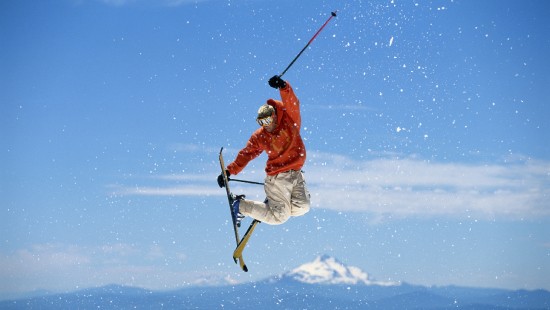 Image man in red jacket and white pants riding ski blades on snow covered ground during daytime