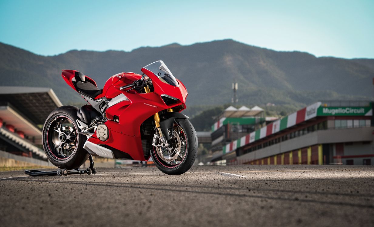 man in red sports bike racing on track field during daytime