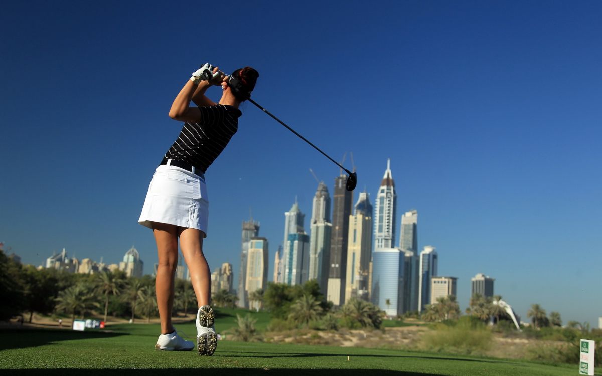 woman in black and white stripe shirt and white shorts holding black and silver golf club