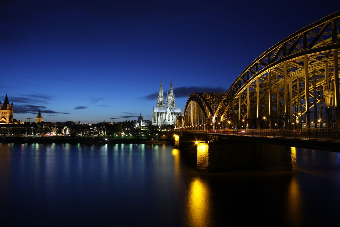 Beleuchtete Brücke Über Wasser Während Der Nacht Night. Wallpaper in 3888x2592 Resolution