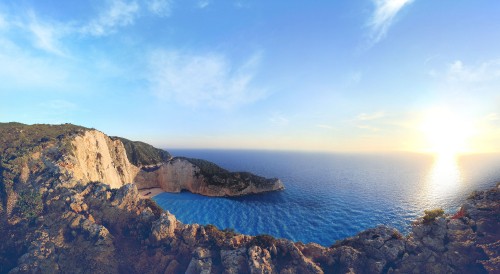 Image brown rocky mountain beside blue sea under blue sky during daytime