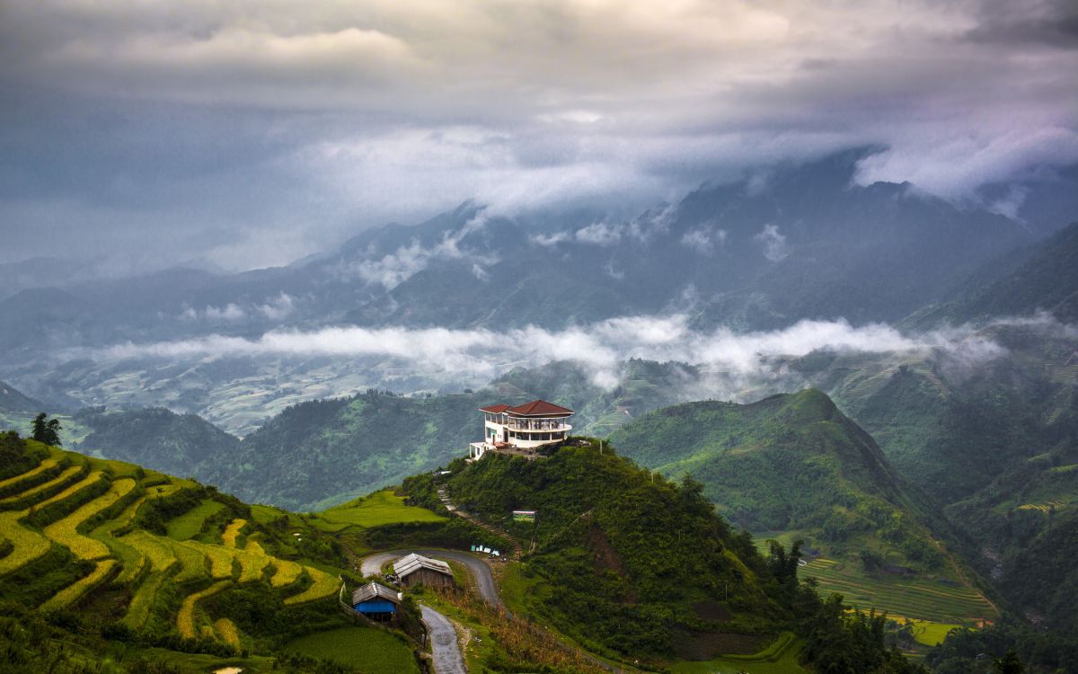 white and brown house on green mountain under white clouds during daytime