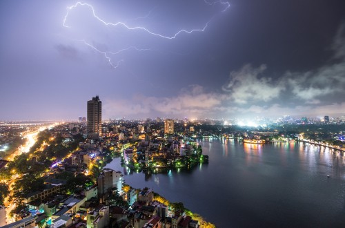 Image city skyline with lightning above during night time