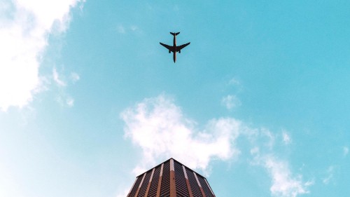 Image airplane flying over the building during daytime