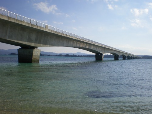 Image gray concrete bridge over the sea under white clouds during daytime