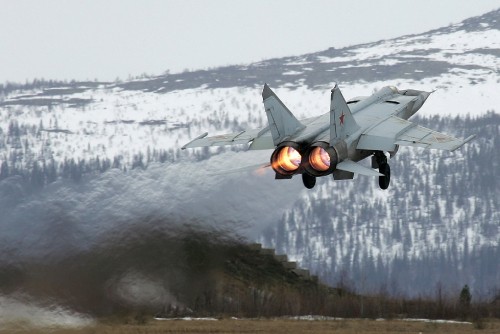 Image gray fighter plane flying over snow covered ground during daytime