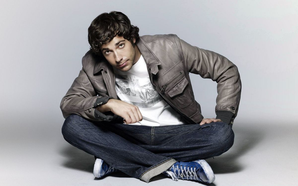 man in gray leather jacket and blue denim jeans sitting on floor