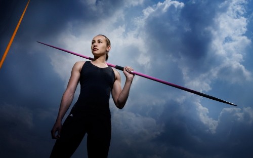 Image woman in black tank top and black pants holding red and white stick