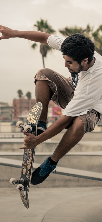 Image man in white t-shirt and brown shorts playing skateboard during daytime