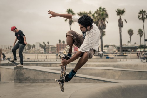 Image man in white t-shirt and brown shorts playing skateboard during daytime