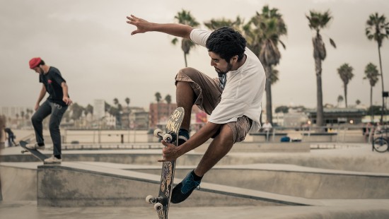 Image man in white t-shirt and brown shorts playing skateboard during daytime