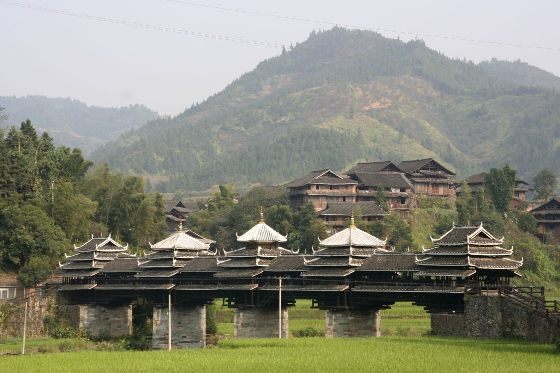 brown wooden house on green grass field near green mountains during daytime