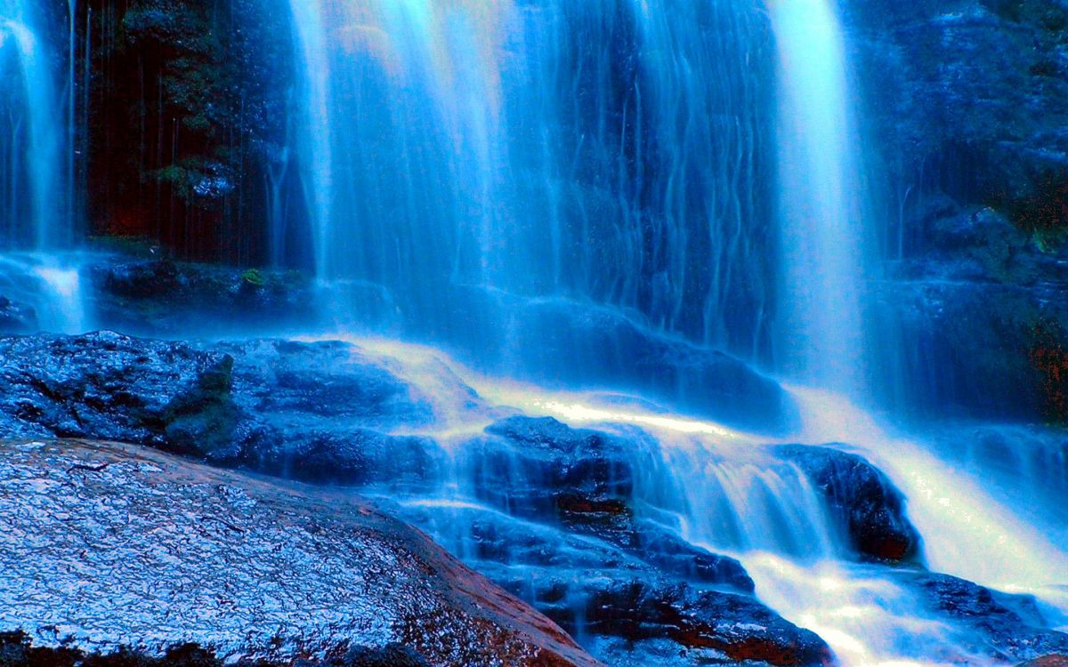 water falls in the middle of rocky shore