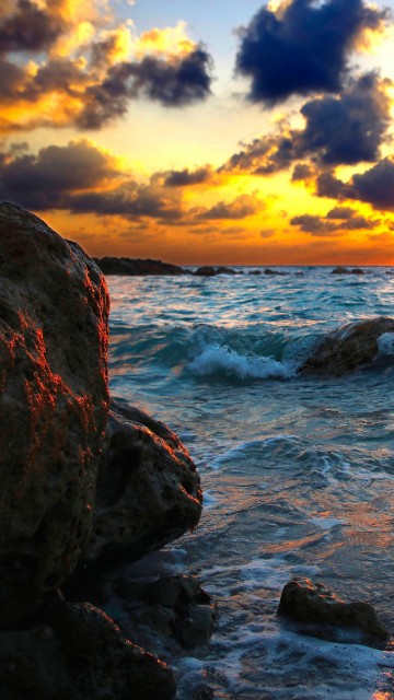 Image rocky shore under cloudy sky during sunset