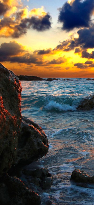 Image rocky shore under cloudy sky during sunset