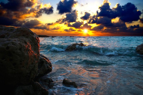 Image rocky shore under cloudy sky during sunset