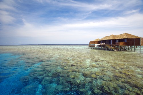 Image brown wooden house on body of water under blue sky during daytime