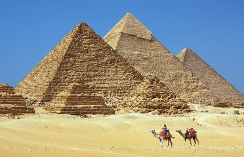 Image people walking on sand near pyramid during daytime