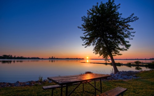 Image brown wooden bench near body of water during sunset