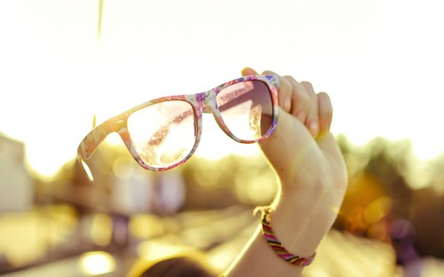 Image person holding brown framed eyeglasses