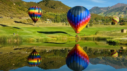 Image hot air balloon flying over green grass field during daytime