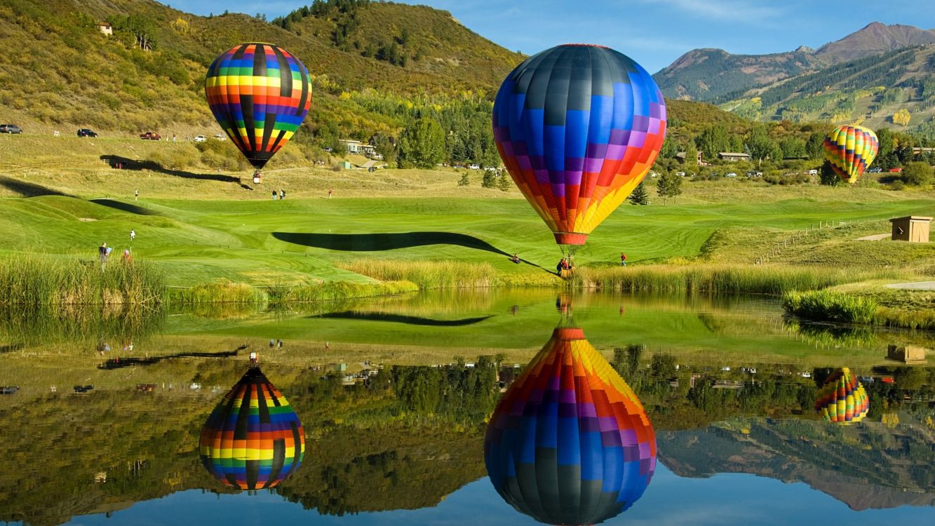 hot air balloon flying over green grass field during daytime