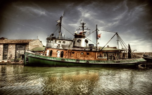 Image green and brown boat on water under gray clouds