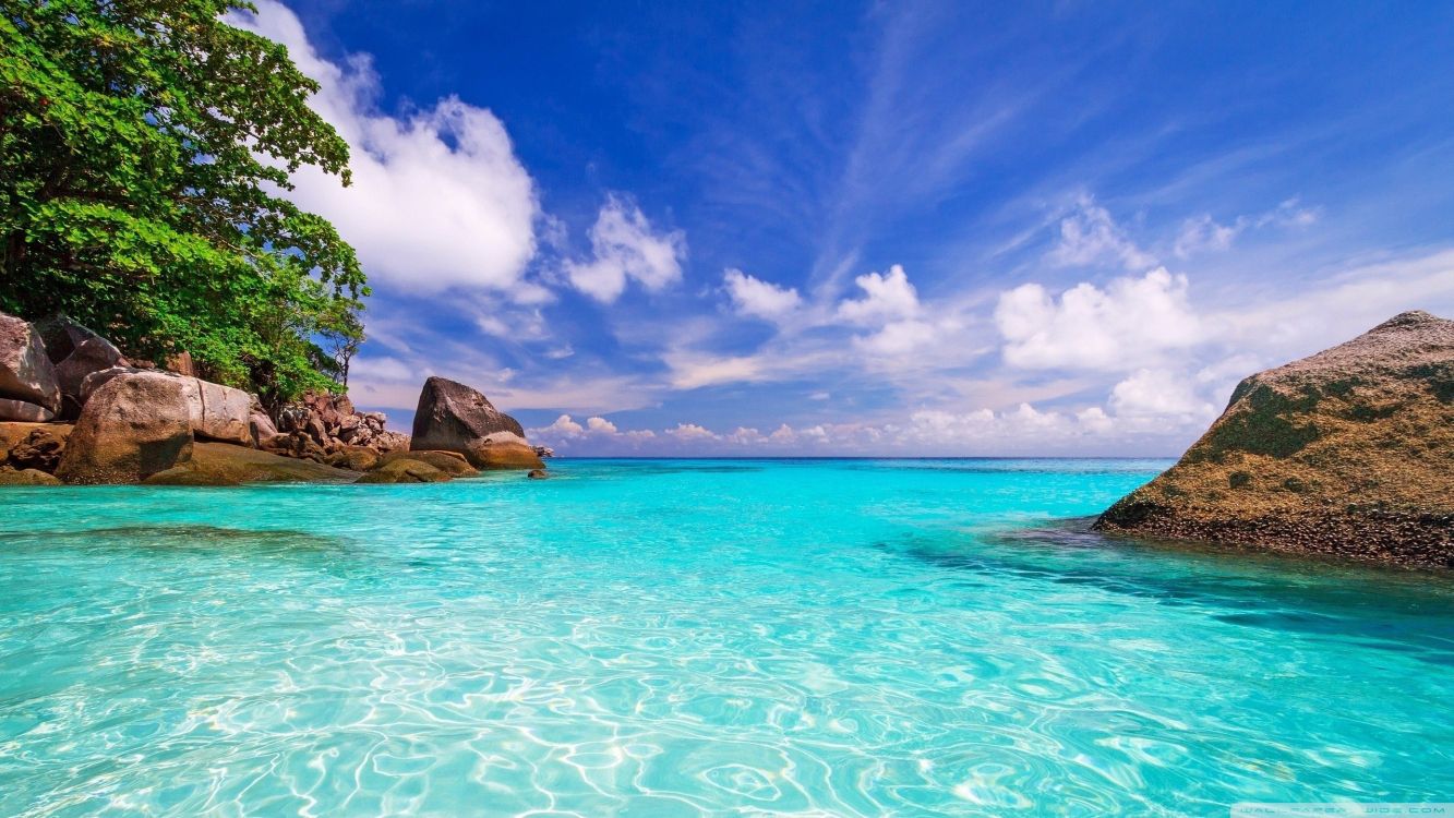 brown rock formation on blue sea under blue sky and white clouds during daytime