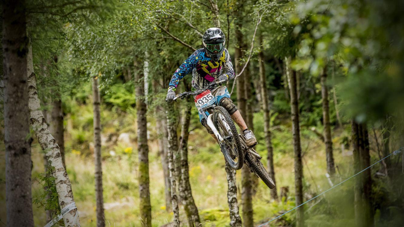 man riding motocross dirt bike in forest during daytime