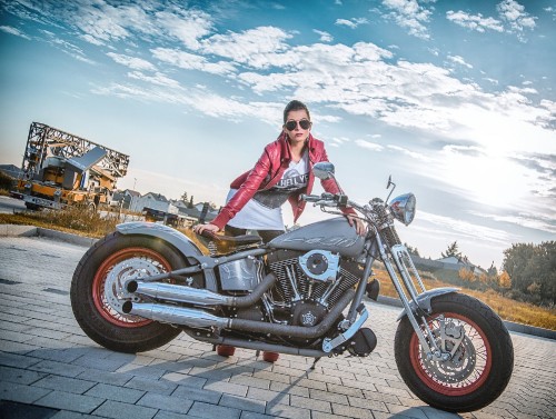 Image woman in pink jacket riding on black cruiser motorcycle