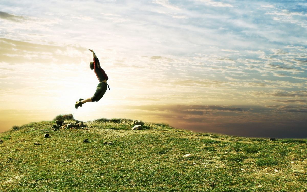 man in black shirt and black pants jumping on green grass field during daytime