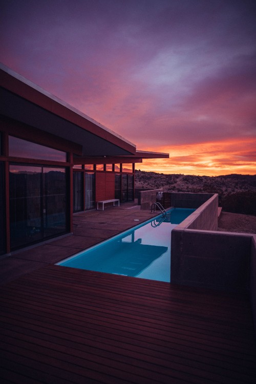 Image swimming pool near brown wooden house during sunset