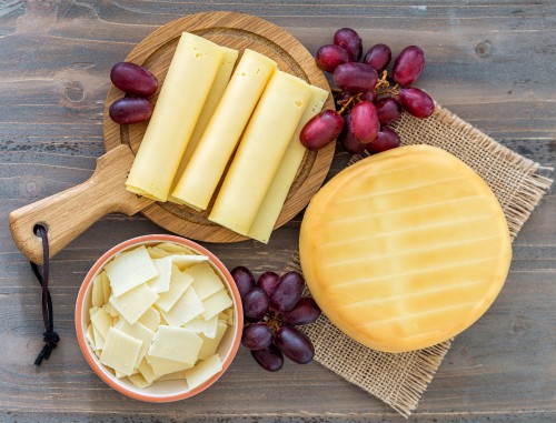 Image sliced cheese on brown wooden chopping board