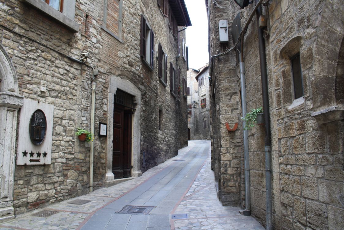 gray concrete pathway between brown brick buildings during daytime